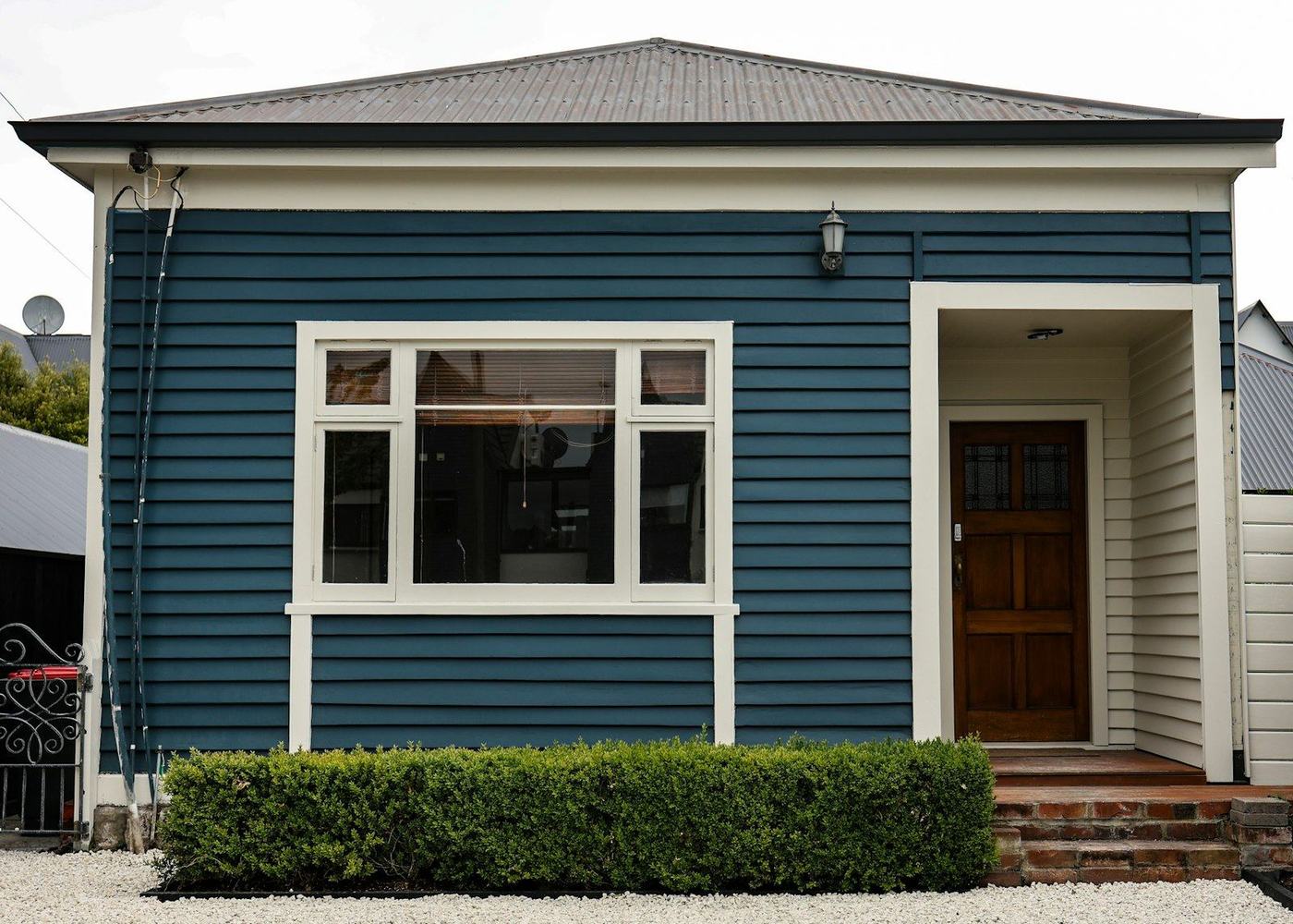 A blue weatherboard villa with a white front door surround